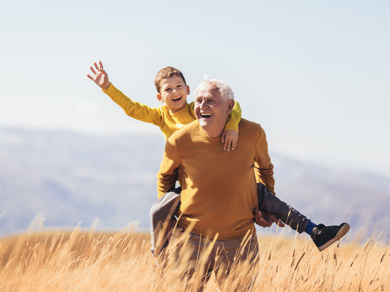 man playing with grandson in field